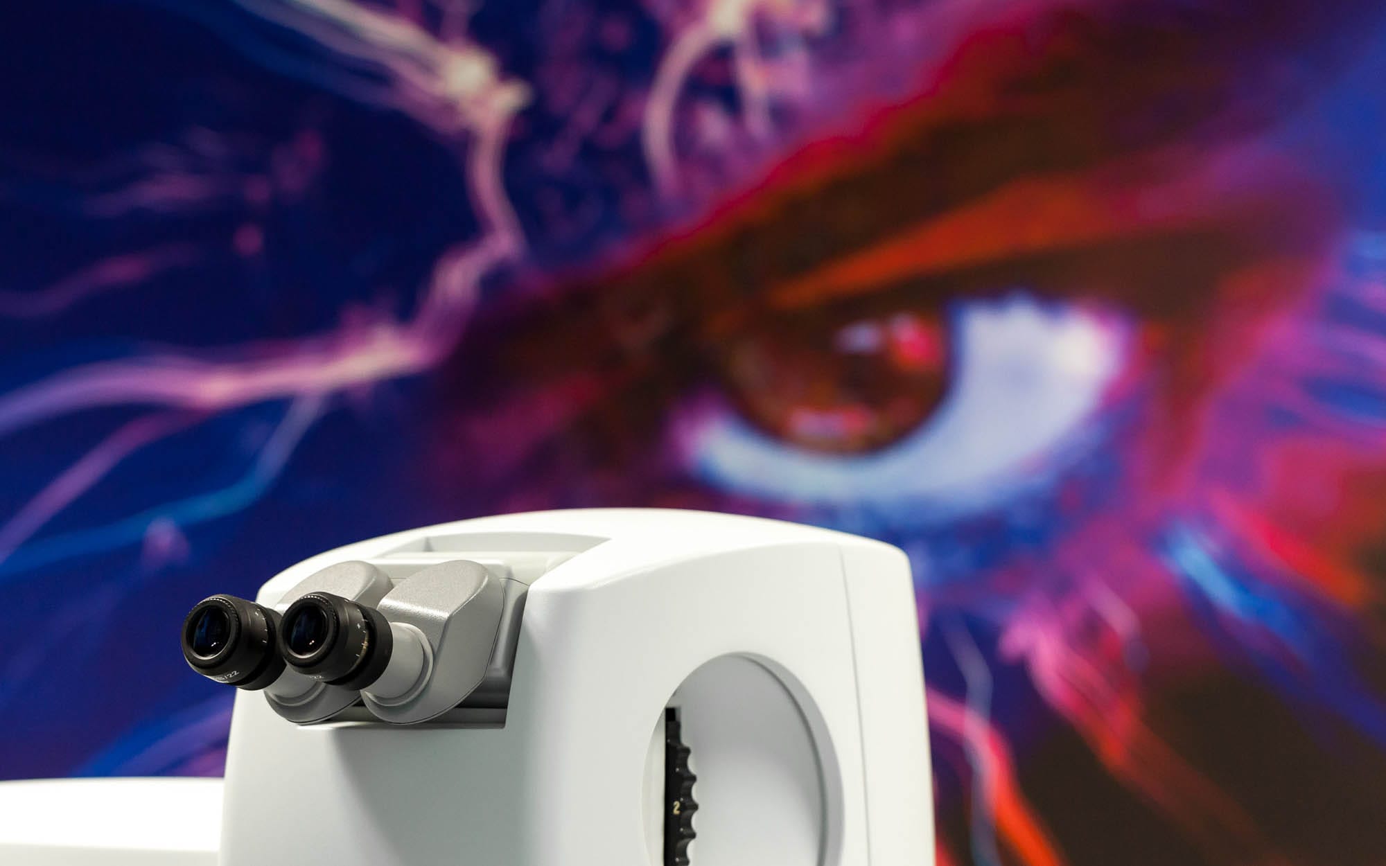 Lasergerät im 5. Obergeschoss der Praxis; im Hintergrund ein Kunstmotiv mit Auge, das die Verbindung von Technik und Sehen symbolisiert.