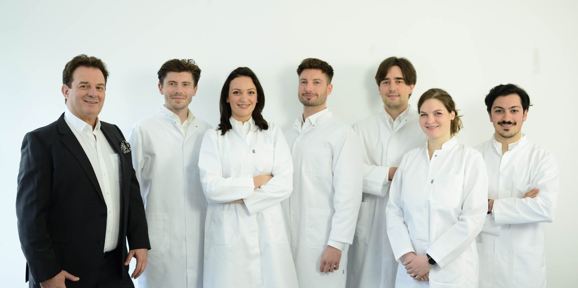 Gruppenfoto des medizinischen Teams in heller Praxisumgebung; mehrere Personen posieren freundlich für das Bild