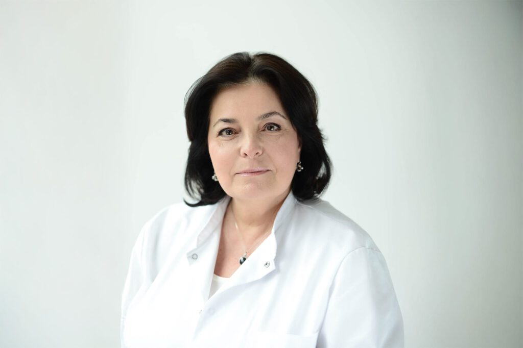 Porträt von Dr. Kogan in professioneller Pose; dezentes Lächeln und ruhiger Hintergrund in der Praxis.
