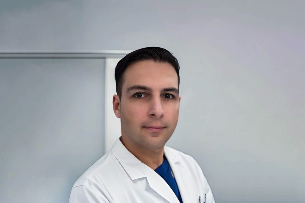Porträt von Dr. A. Lukic, Ärztin im weißen Kittel; freundlicher Blick vor neutralem Hintergrund in heller Praxisumgebung.